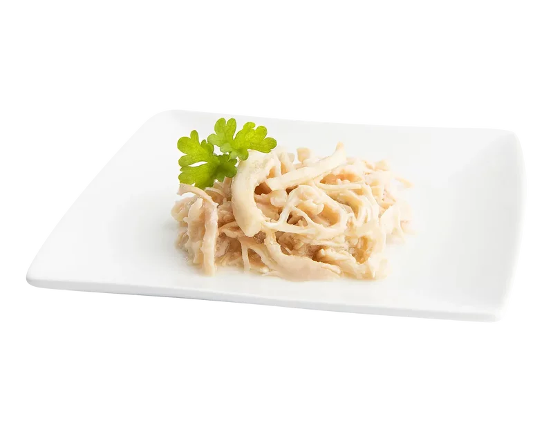 Weiße Hühnerstreifen auf weißem rechteckigem Teller mit grünem Petersilienblatt.